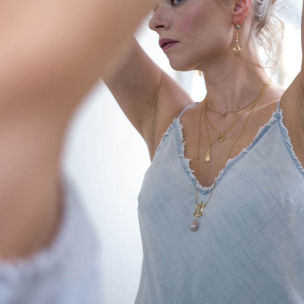woman wearing layered necklaces in gold and diamonds and elegant gold and diamond earrings with gray rose cut diamonds from Nikki Lorenz Designs