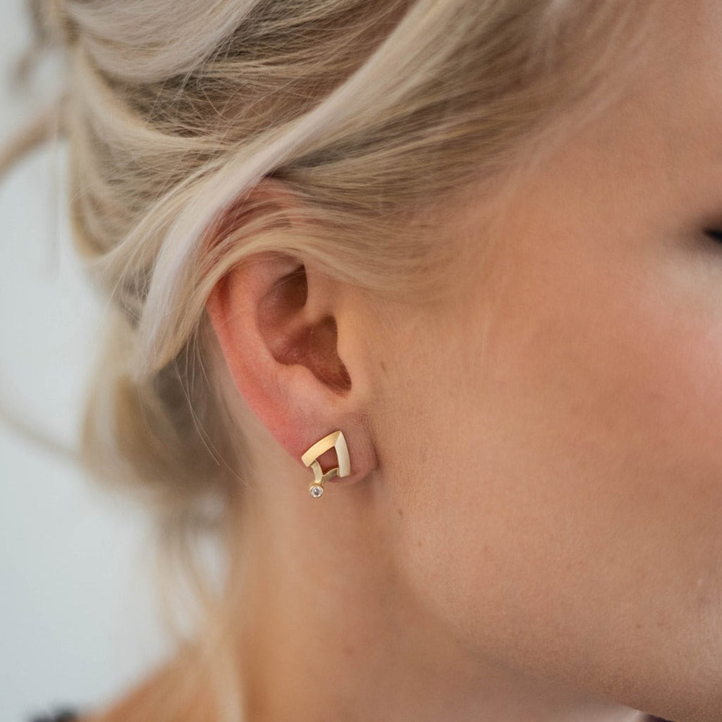 woman wearing small shield shaped gold and diamond earring from Nikki Lorenz Designs