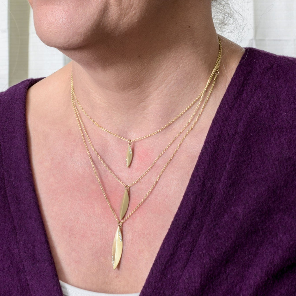 model wearing 3 sizes of an 14k gold elongated pendant from Nikki Lorenz Designs