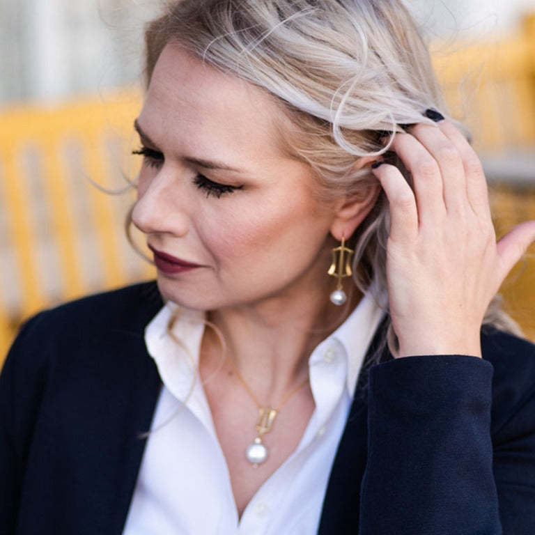 woman in suit wearing gold south sea pearl earrings and gold, pearl, and diamond necklace from Nikki Lorenz Designs