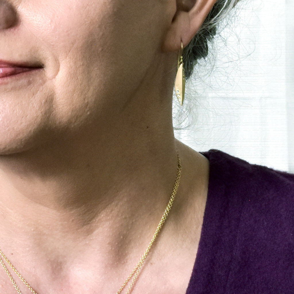 model wearing elongated gold and diamond earrings from Nikki Lorenz Designs